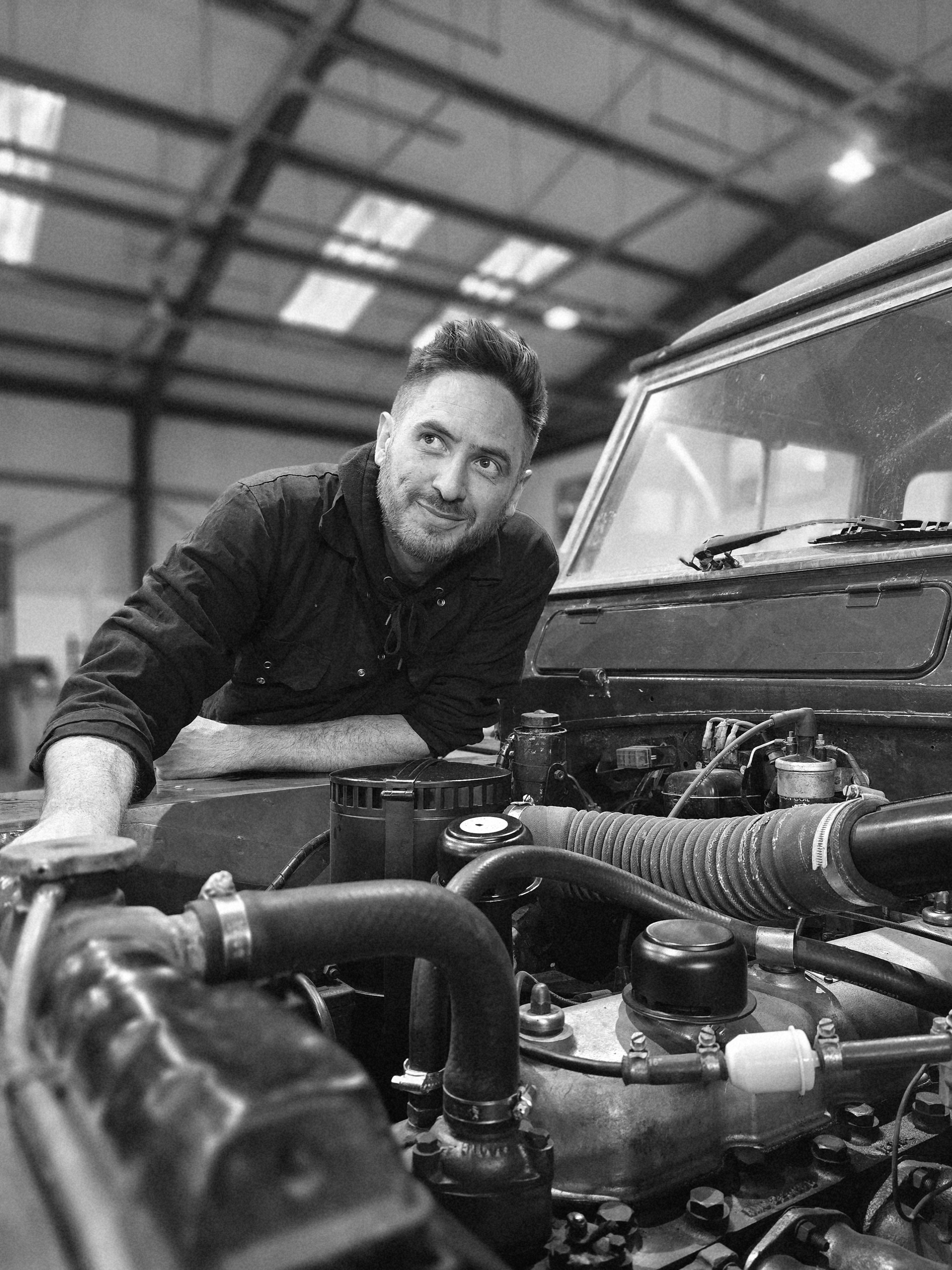 Luke beside a classic vehicle in the workshop